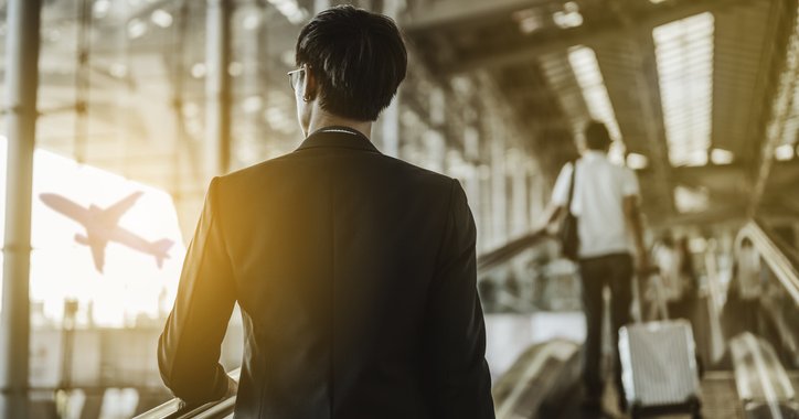 A man with a suitcase walking through a sunny airport.