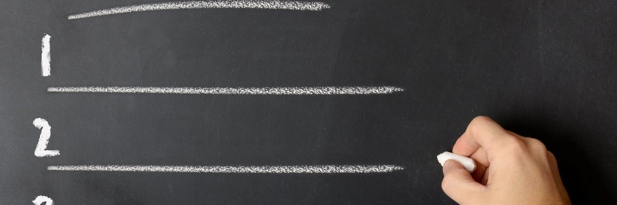 Man writing a list of rules on a chalkboard.