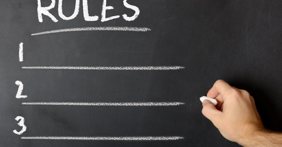 man writing a list of rules on a chalkboard.