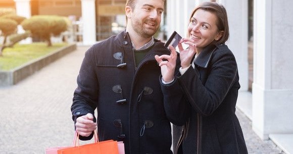 young couple shopping with both hands on a credit card
