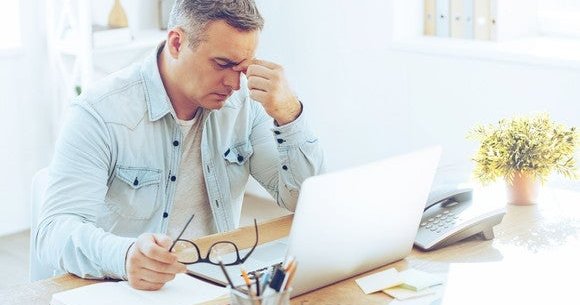 Mature man sitting at computer looking frustrated