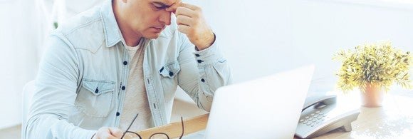 Mature man sitting at computer looking frustrated
