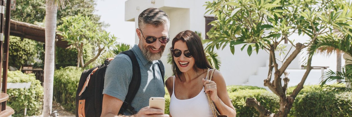mature man and woman taking a selfie in front of a hotel and palm trees