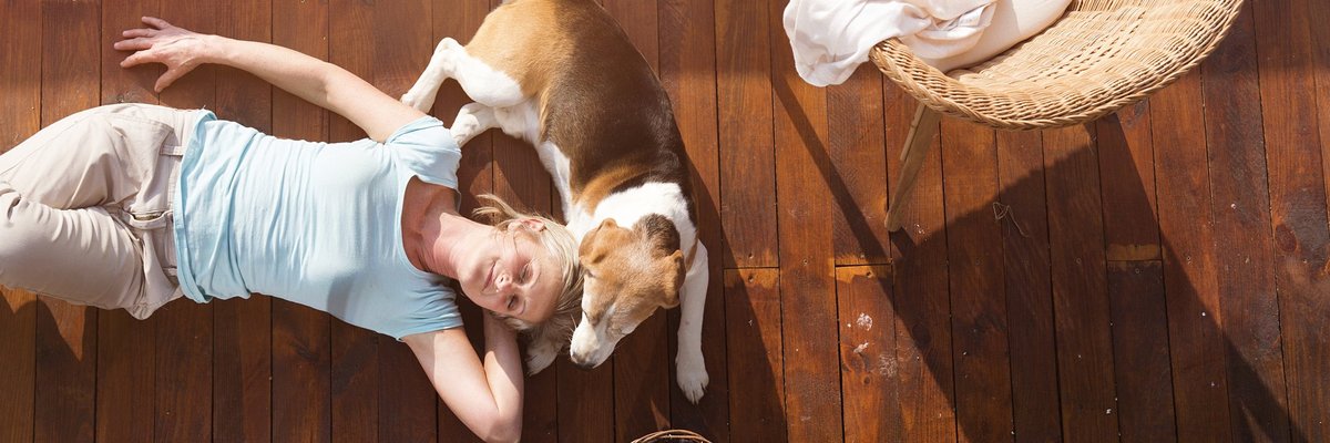 mature woman lying down on deck with her head resting against a beagle -- pet dog owner