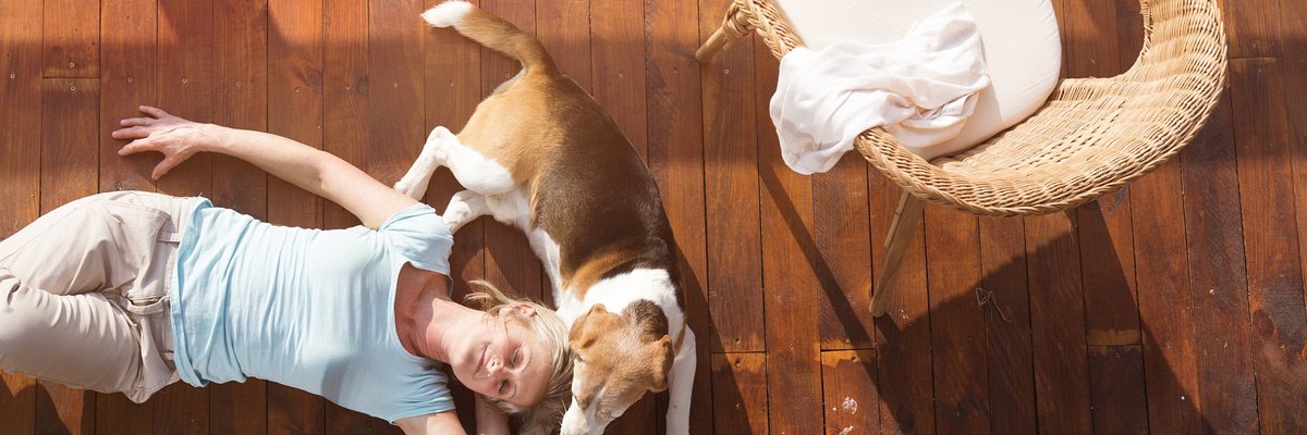 Mature woman lies down on a deck with her head resting against her beagle