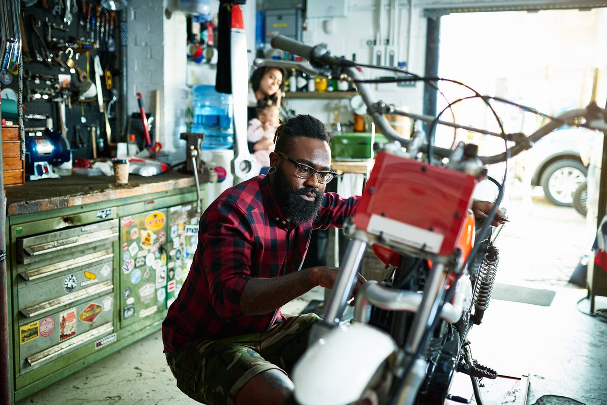 A mechanic working on a motorcycle in an auto shop.