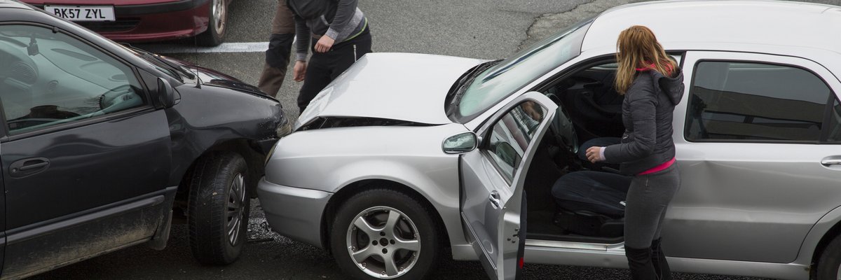 People getting out of their cars to look at the damage from a fender bender on the road.