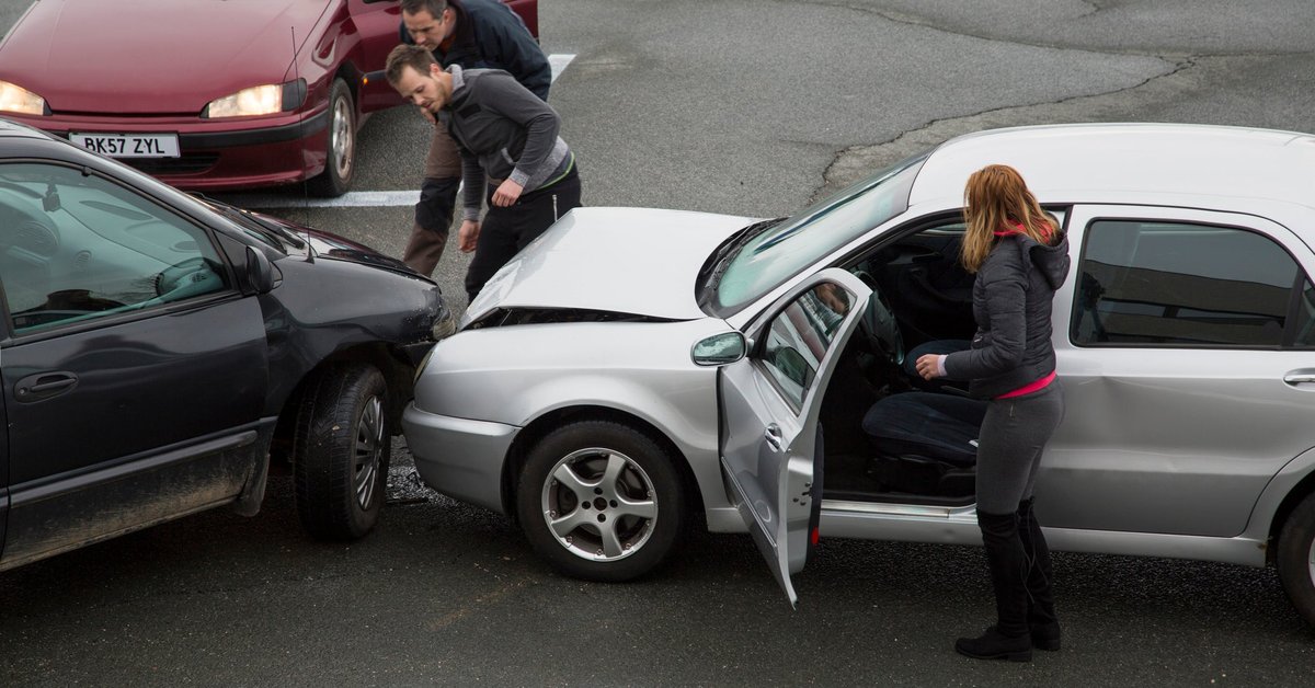 People getting out of their cars to look at the damage from a fender bender on the road.