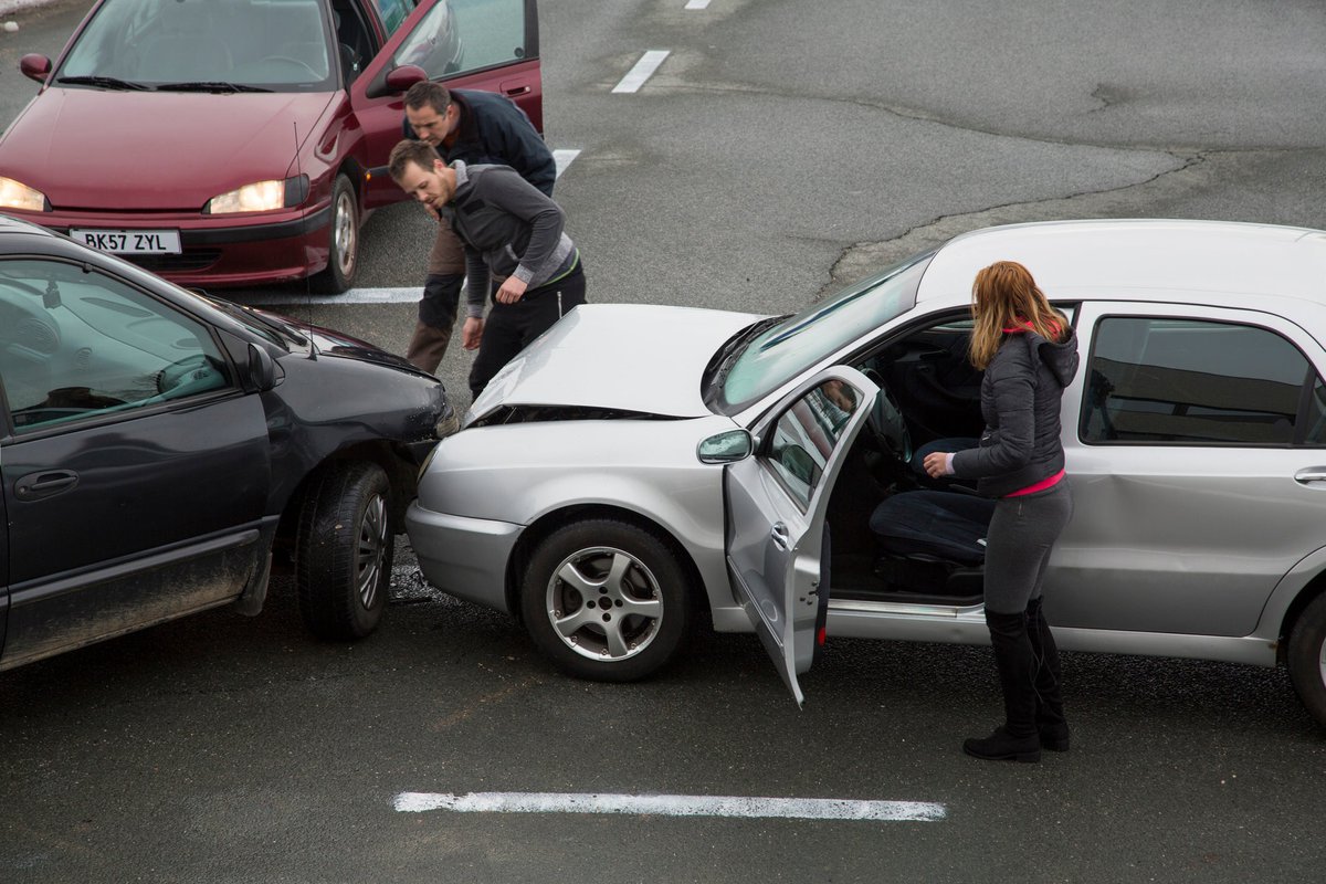 People getting out of their cars to look at the damage from a fender bender on the road.