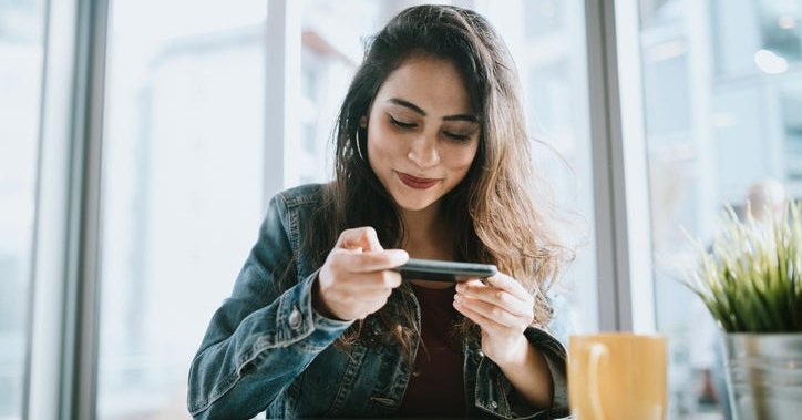 A young woman taking a picture of a  check.