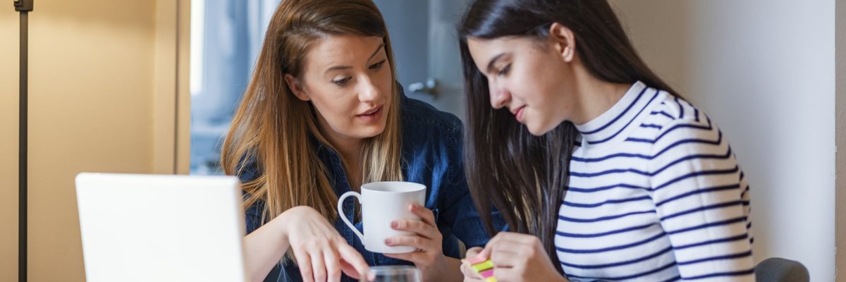 A mom chatting with her teen daughter as she works on her homework.