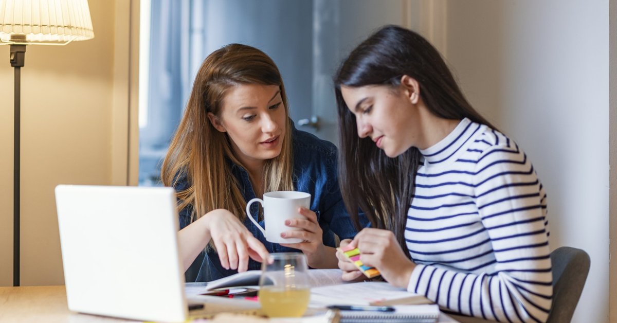 A mom chatting with her teen daughter as she works on her homework.