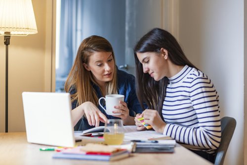 A mom chatting with her teen daughter as she works on her homework.