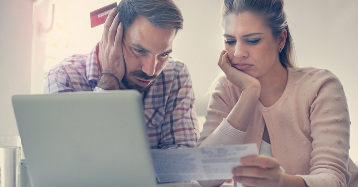 A worried man and woman looking at bills and a laptop