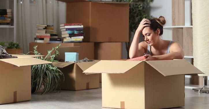 A distressed woman surrounded by moving boxes.