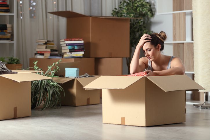 A distressed woman surrounded by moving boxes.
