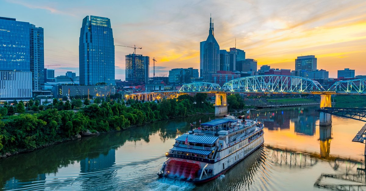A ferry boat going up the river alongside downtown Nashville, Tennessee, at dusk.