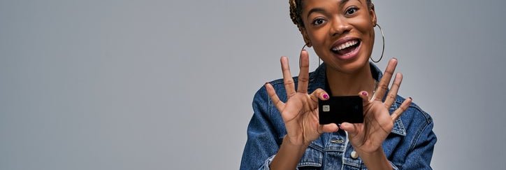 A woman smiling and holding up a credit card.