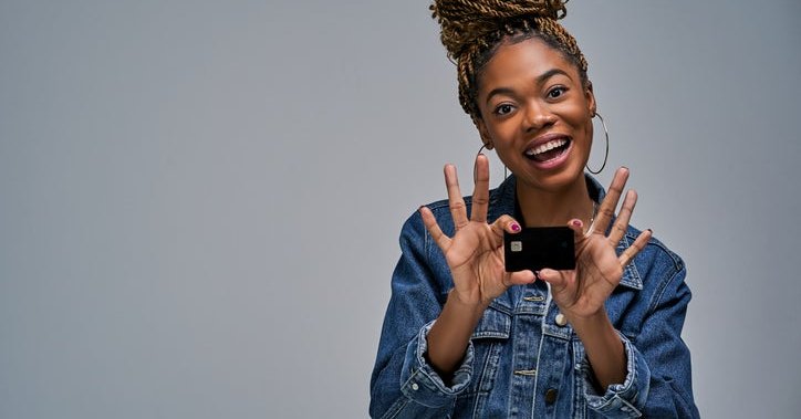 A woman smiling and holding up a credit card.