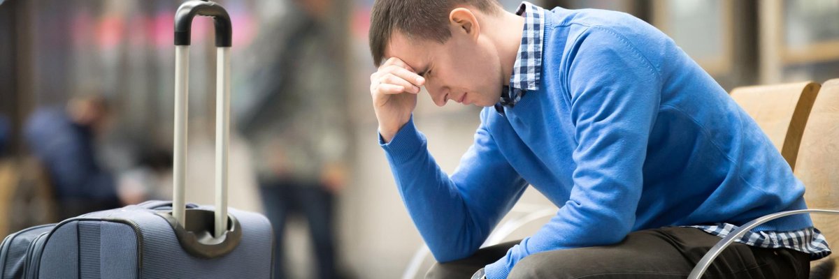 pained young man beside suitcase in airport