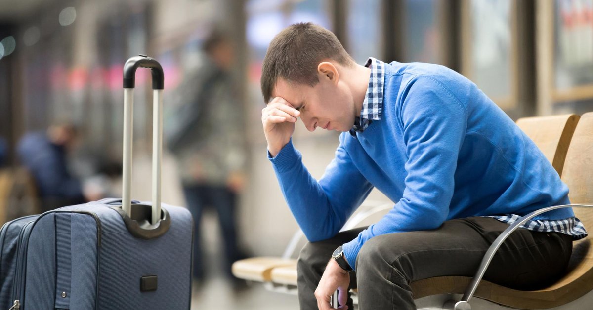 pained young man beside suitcase in airport