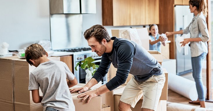 A mom, dad, son, and daughter packing moving boxes in the kitchen.