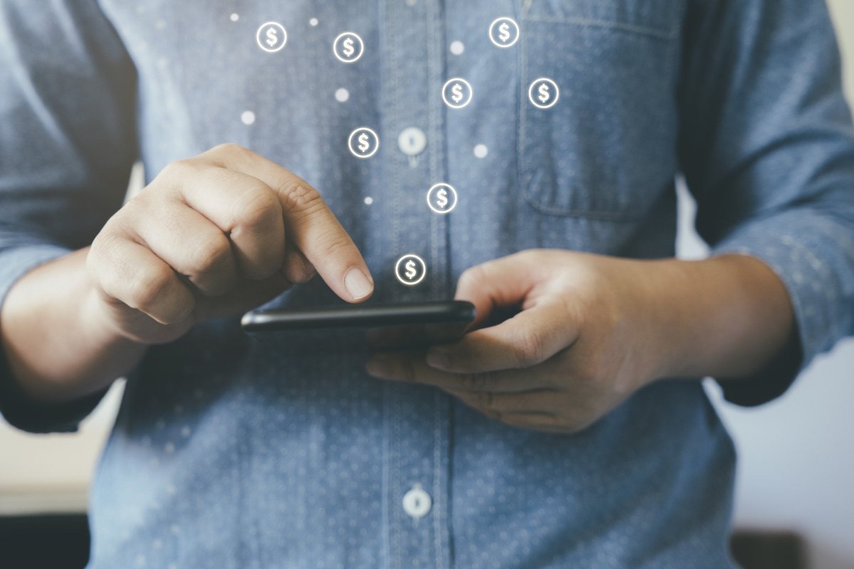 Man making online payment with dollar signs floating out of smartphone.