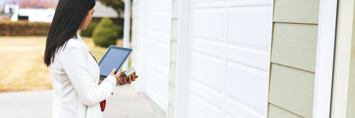 A home appraiser standing outside the garage of a home.