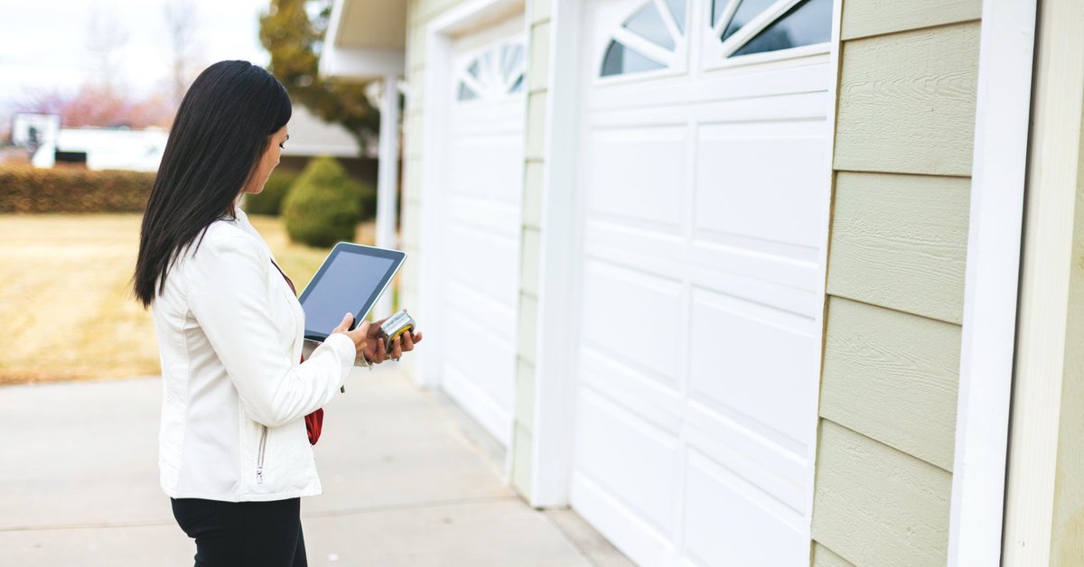 A home appraiser standing outside the garage of a home.