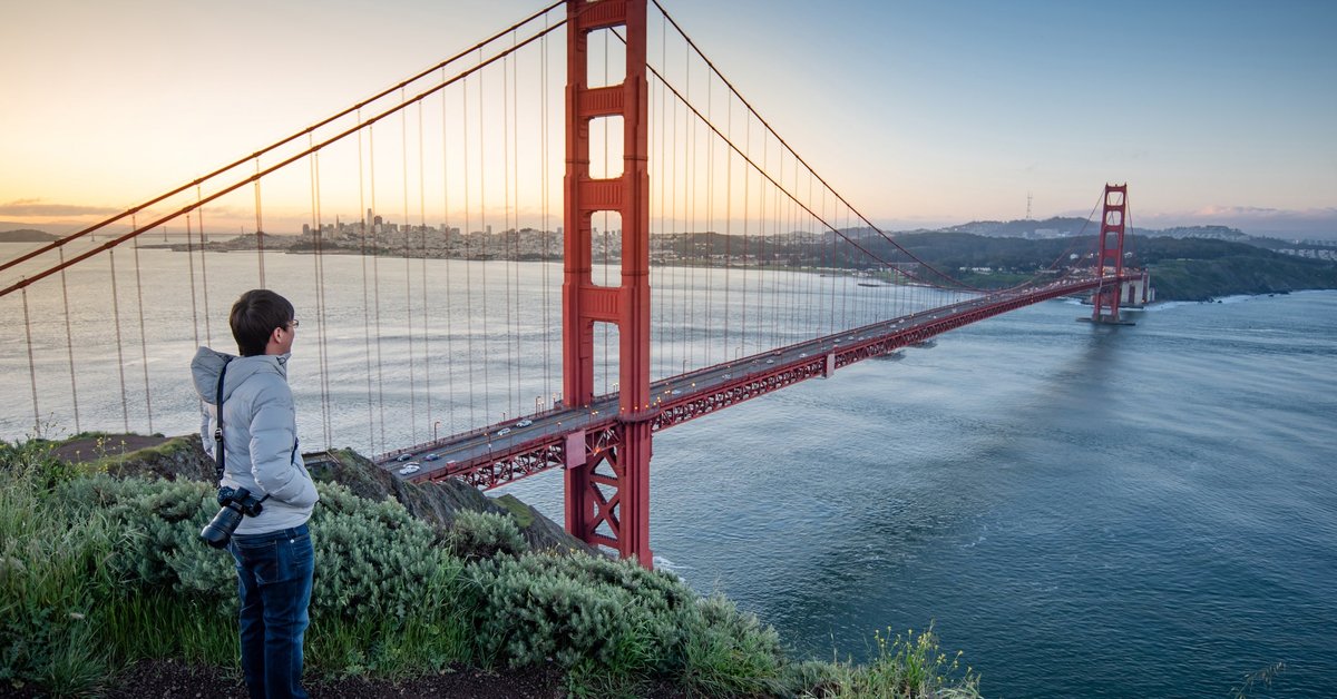 A person standing at an overlook taking in the view of the Golden Gate Bridge.