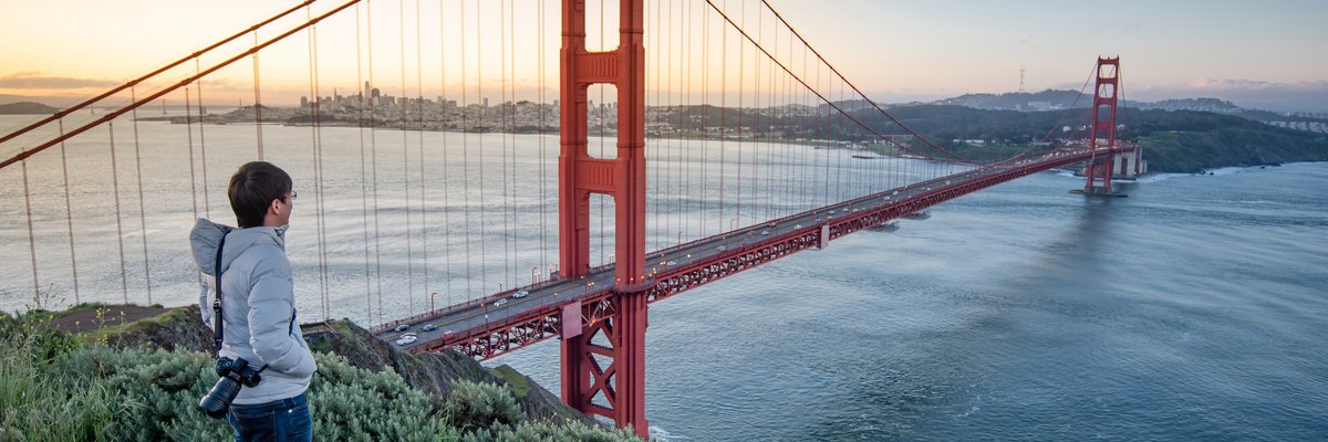 A person standing at an overlook taking in the view of the Golden Gate Bridge.