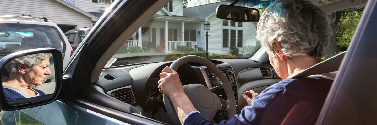 A person pulling their car out of the driveway in front of their house.