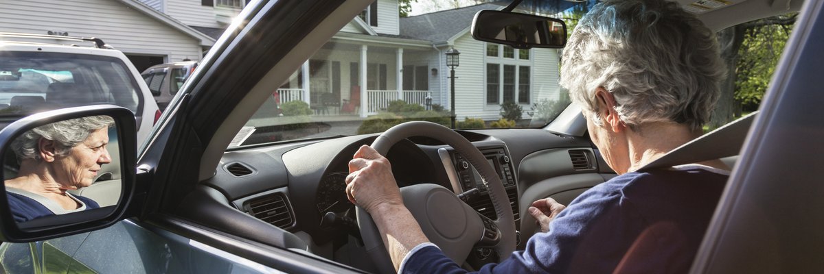 A person pulling their car out of the driveway in front of their house.