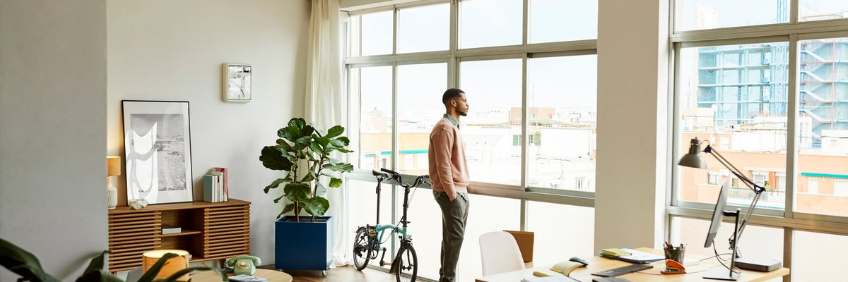 A person standing and looking out the window of their apartment.
