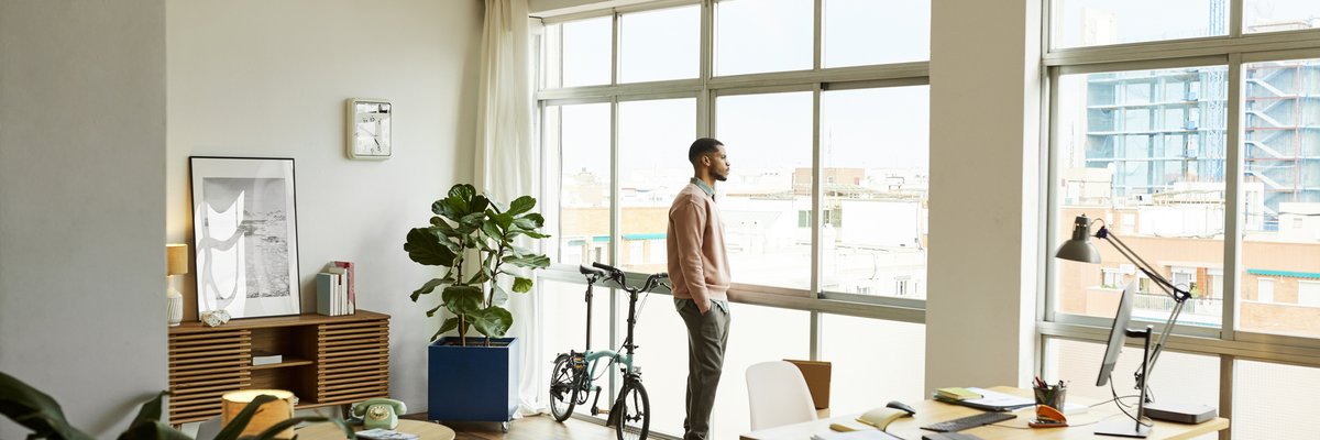 A person standing and looking out the window of their apartment.