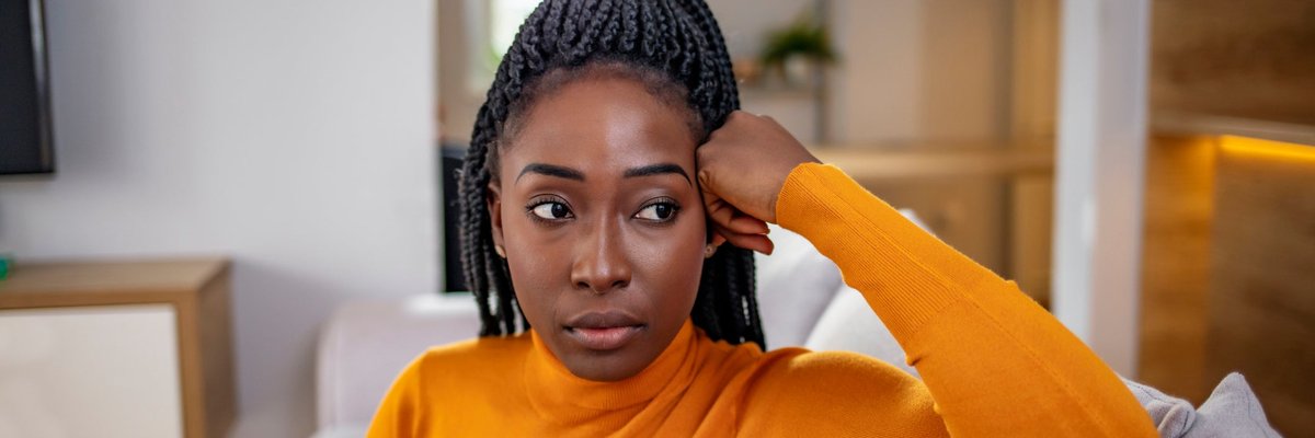 A person looking stressed and thoughtful while sitting on their couch.
