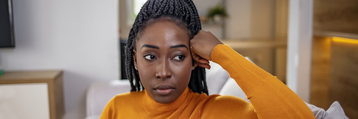 A person looking stressed and thoughtful while sitting on their couch.