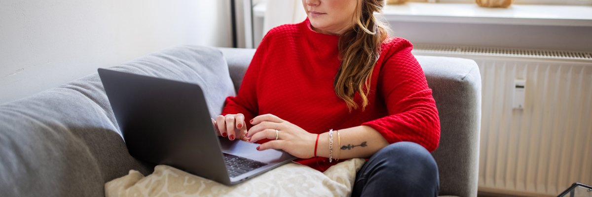 A person typing on a laptop while sitting comfortably on a couch.