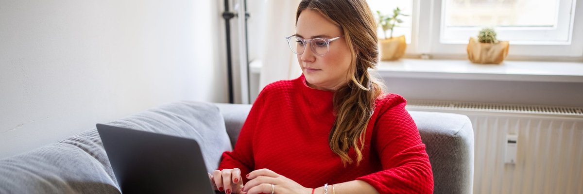 A person typing on a laptop while sitting comfortably on a couch.