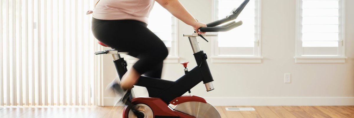 A person on an exercise bike in their living room at home.