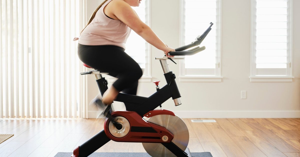A person on an exercise bike in their living room at home.