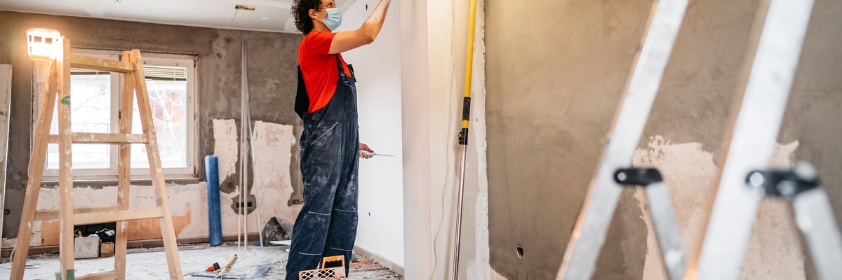 A person putting up drywall in a home renovation.