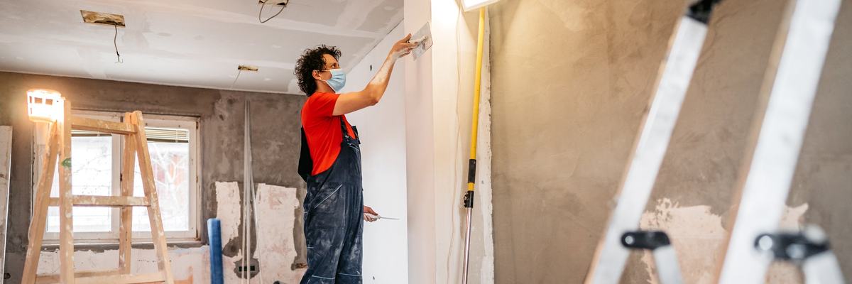 A person putting up drywall in a home renovation.