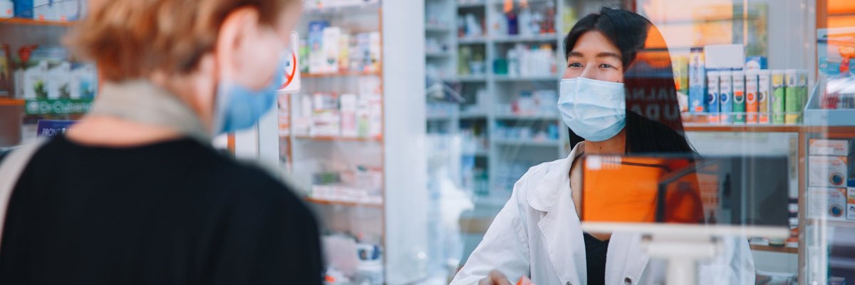 A person speaking with a pharmacist and getting medicine.