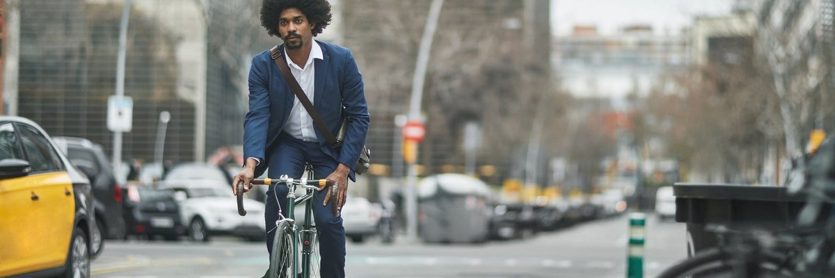 A person wearing business clothes and riding a bike on a city street.