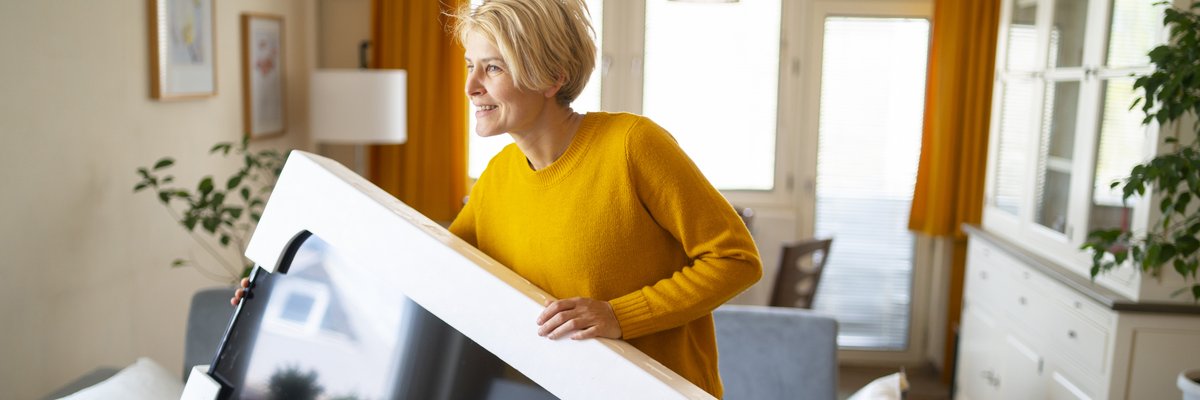 A person taking a new TV out of the box in their living room.