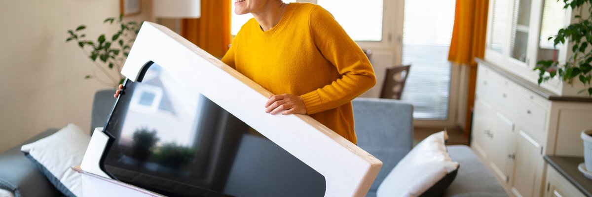 A person taking a new TV out of the box in their living room.