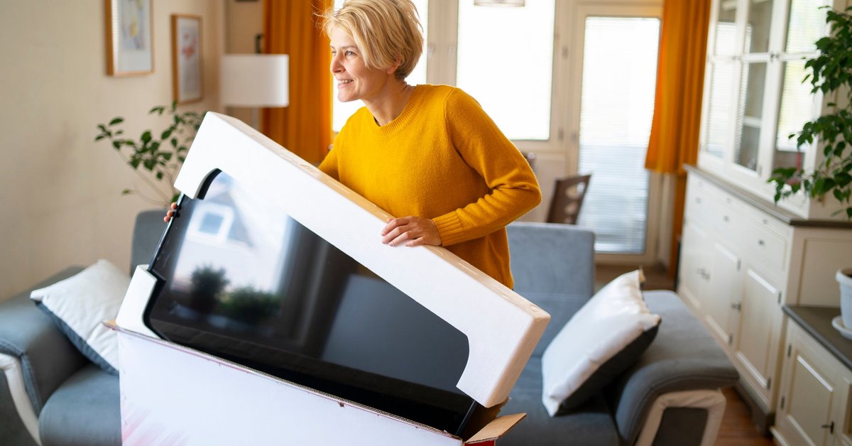 A person taking a new TV out of the box in their living room.