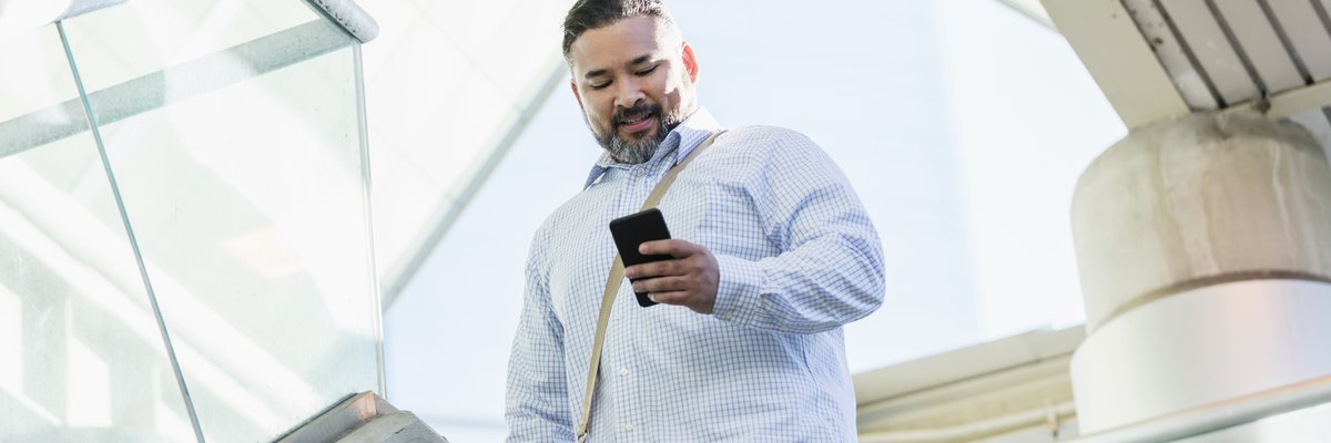A person walking down stairs while smiling and looking at their phone.