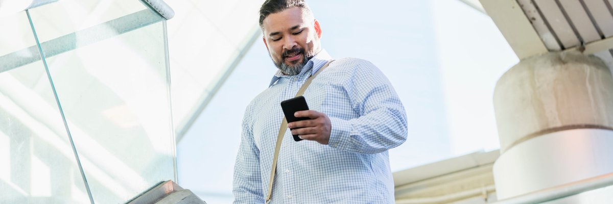 A person walking down stairs while smiling and looking at their phone.